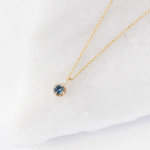 Blue sapphire necklace in yellow gold on marble side view 