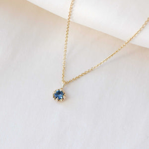 Blue sapphire necklace in yellow gold on white fabric side view 