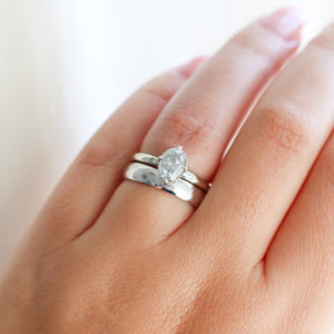 Oval grey diamond ring with wide wedding band on hand