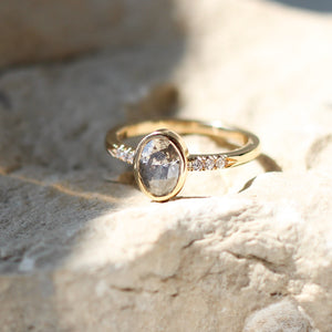 Oval salt and pepper diamond ring in sunlight on stone
