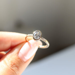 Oval salt and pepper diamond ring in sunlight in hand