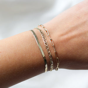 Paper Clip Chain Bracelet paired with golden bracelets on hand 