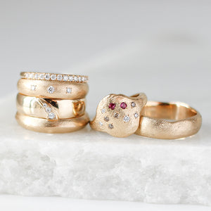 Beach Textured Wide Band in group shot with other wide gold diamond rings and stacking bands on marble