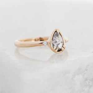 Pear cut diamond ring in yellow gold on marble quarter view