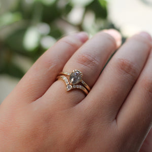 Pear diamond ring in yellow gold paired with diamond gold stacking band on hand in sunlight