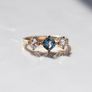 Blue Cushion Cut Montana Sapphire Three Stone Ring quarter view with reflections in sunlight