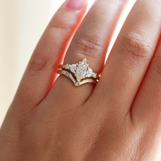 Yellow gold ring with a champagne marquise cut diamond and white diamond clusters stacked with pointed wedding band with three round white diamonds, on hand