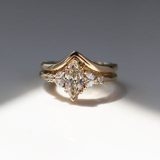Yellow gold ring with a champagne marquise cut diamond and white diamond clusters stacked with pointed wedding band, front view