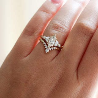 Yellow gold ring with a champagne marquise cut diamond and white diamond clusters stacked with pointed wedding band with white diamonds, on hand