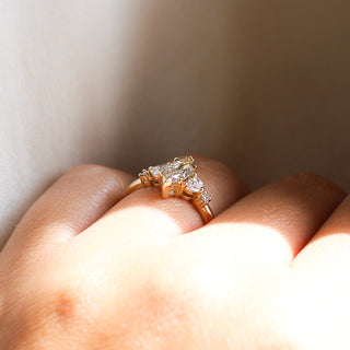 Yellow gold ring with a champagne marquise cut diamond and white diamond clusters, side view on hand