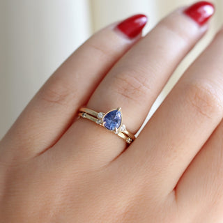 Pear Cut Purple Sapphire ring paired with diamond gold band worn on hand 