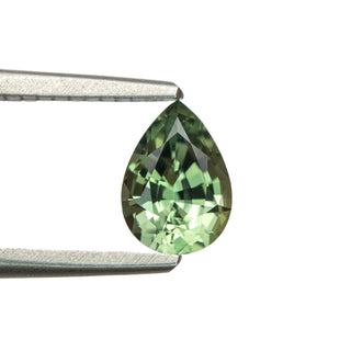 Green pear cut sapphire in tweezers
