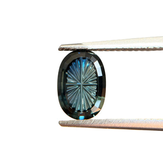 Teal fantasy cut oval sapphire in tongs