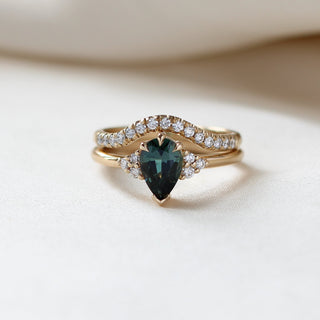 Pear Teal Green Sapphire Ring with diamond gold band stacked on fabric 