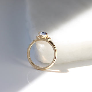 Three stone yellow gold ring with pear cut blue sapphire and white round diamond accents, side view