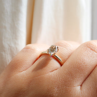 Yellow gold solitaire engagement ring with an oval champagne diamond, quarter view on hand 