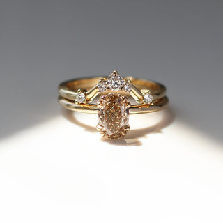 Yellow gold solitaire engagement ring with an oval champagne diamond stacked with a curved wedding band with five white round diamonds, front view