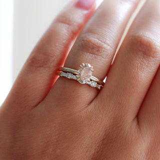 Yellow gold solitaire engagement ring with an oval champagne diamond stacked with a straight wedding band with alternating round and baguette white diamonds, on hand