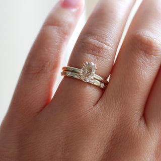 Yellow gold solitaire engagement ring with an oval champagne diamond stacked with a straight wedding band with star-set round white diamonds, on hand