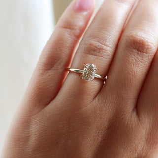 Yellow gold solitaire engagement ring with an oval champagne diamond, on hand