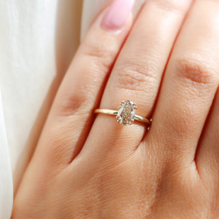 Yellow gold solitaire engagement ring with an oval champagne diamond, on hand