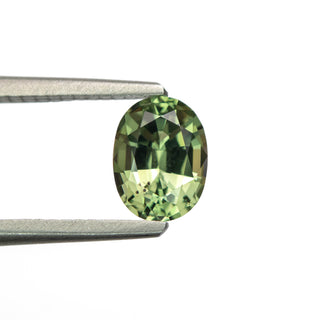 Green oval brilliant cut sapphire in tweezers