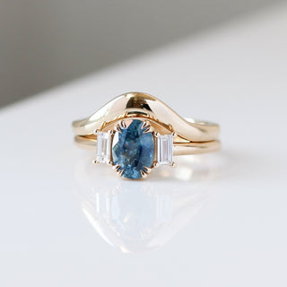 Oval Cut Blue Sapphire Ring paired with wave gold band quarter view