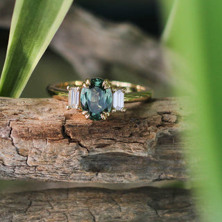 Trilogy Oval Green Sapphire Ring on a branch with green leaves detailed front view