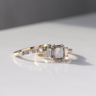Emerald cut salt and pepper diamond ring in yellow gold paired with gold diamond stacker band close up