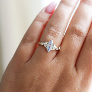 Yellow gold ring with a light blue marquise cut sapphire and white diamond clusters, on hand