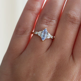 Yellow gold ring with a light blue marquise cut sapphire and white diamond clusters, on hand