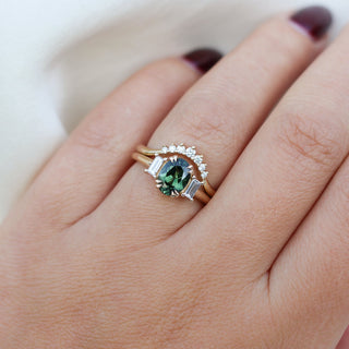Oval cut green sapphire ring with baguette side stones in yellow gold stacked with curved diamond wedding band, on hand