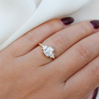 Emerald cut lab diamond ring with baguette and round brilliant cut side stones in yellow gold, on hand