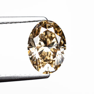 Oval champagne diamond held by tweezers on a white background