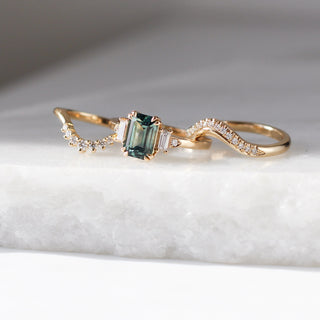 Emerald Cut Teal Sapphire Ring paired with two gold diamond bands on marble quarter view