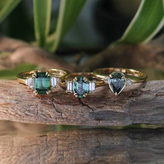 Misceo Emerald Cut Green Sapphire Ring stacked with Oval and Pear Cut Rings on a branch with reflections detailed front view