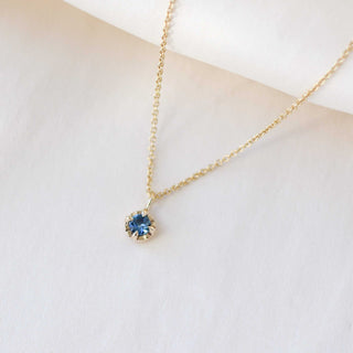 Blue sapphire necklace in yellow gold on white fabric side view 