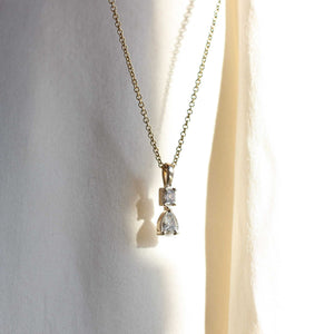 Emerald cut and pear necklace in yellow gold in sun light side view