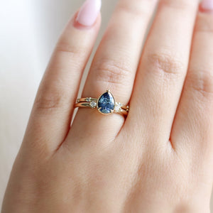 five diamond wedding band and pear blue sapphire ring on hand