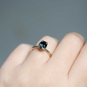 Teal sapphire solitaire on hand detail view