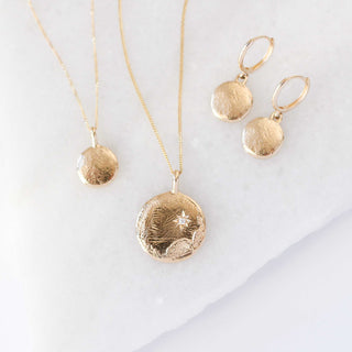 Golden drop earrings and textured golden tecklace side view close up 