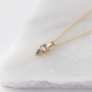 Emerald and pear cut diamond necklace in yellow gold  on marble quarter view 