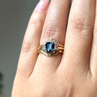 Emerald Cut Blue Sapphire Ring paired with diamond gold bands on hand in sunlight