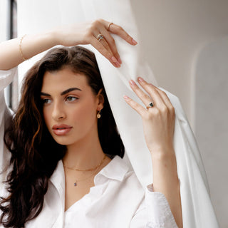 Oval salt and pepper diamond ring worn on hand against white fabric