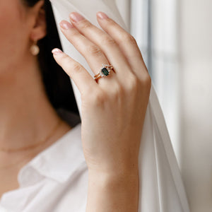 Emerald cut green sapphire engagement ring with wedding band on hand