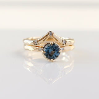 Round blue spinel ring in yellow gold stacked with pointed 3-diamond wedding band, front view