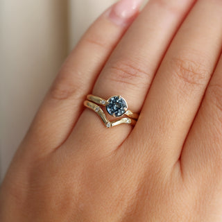 Round blue spinel ring in yellow gold stacked with pointed 3-diamond wedding band, on hand