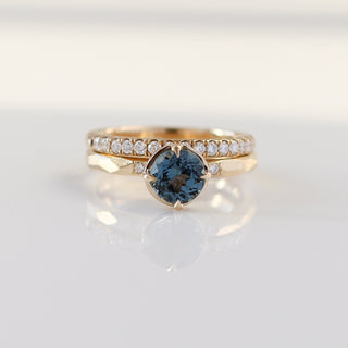 Round blue spinel ring in yellow gold stacked with straight diamond pave wedding band, front view