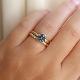 Round blue spinel ring in yellow gold stacked with straight star-set diamond wedding band, on hand