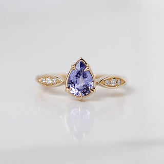 One yellow gold engagement ring with a purple pear shaped sapphire and diamond accents, front view